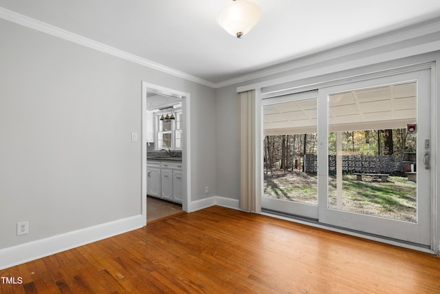 empty room featuring sink, hardwood / wood-style floors, and ornamental molding