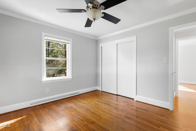 unfurnished bedroom with ceiling fan, hardwood / wood-style flooring, baseboard heating, and a closet