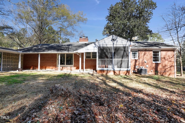 rear view of house featuring a yard, a sunroom, and central AC