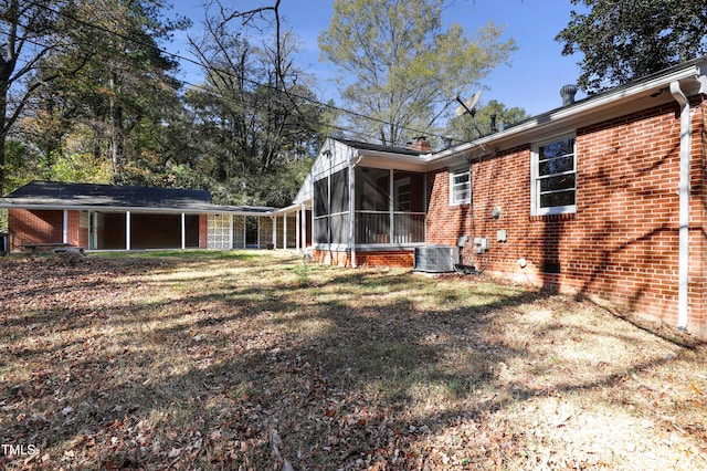 rear view of property featuring central AC unit and a sunroom