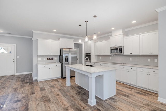 kitchen with appliances with stainless steel finishes, a center island with sink, decorative light fixtures, hardwood / wood-style flooring, and white cabinets