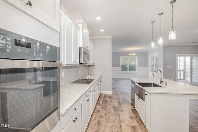 kitchen featuring white cabinets, a wealth of natural light, an island with sink, and stainless steel appliances