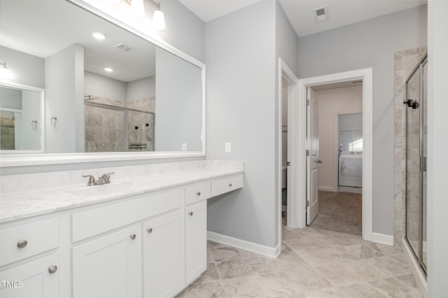 bathroom with vanity, washer / clothes dryer, and a shower with shower door