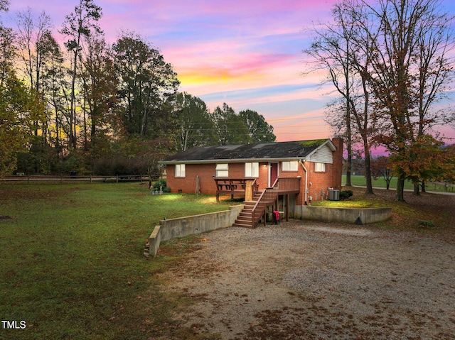 view of front of home with a yard, central AC unit, and a wooden deck