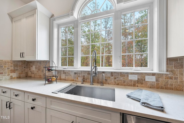 kitchen featuring decorative backsplash, white cabinetry, and sink