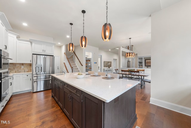 kitchen with a kitchen island with sink, dark hardwood / wood-style flooring, hanging light fixtures, and stainless steel refrigerator with ice dispenser