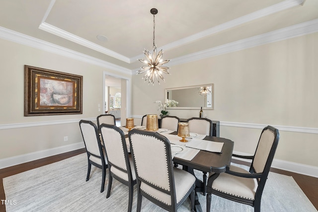 dining space featuring a tray ceiling, crown molding, dark hardwood / wood-style flooring, and a notable chandelier