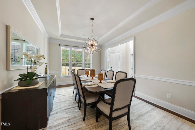 dining room featuring wood-type flooring, ornamental molding, a tray ceiling, and an inviting chandelier