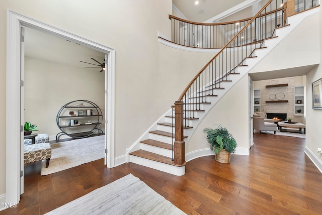 stairs featuring a high ceiling, a large fireplace, and hardwood / wood-style flooring