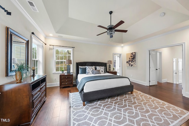 bedroom with dark hardwood / wood-style floors, ceiling fan, a raised ceiling, and crown molding