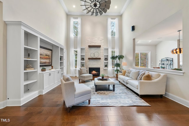 living room featuring a stone fireplace, plenty of natural light, a chandelier, and dark hardwood / wood-style floors