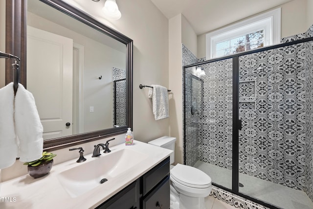 bathroom with tile patterned floors, a shower with door, vanity, and toilet