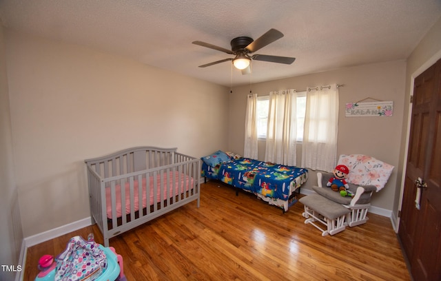 bedroom with ceiling fan, wood-type flooring, and a textured ceiling