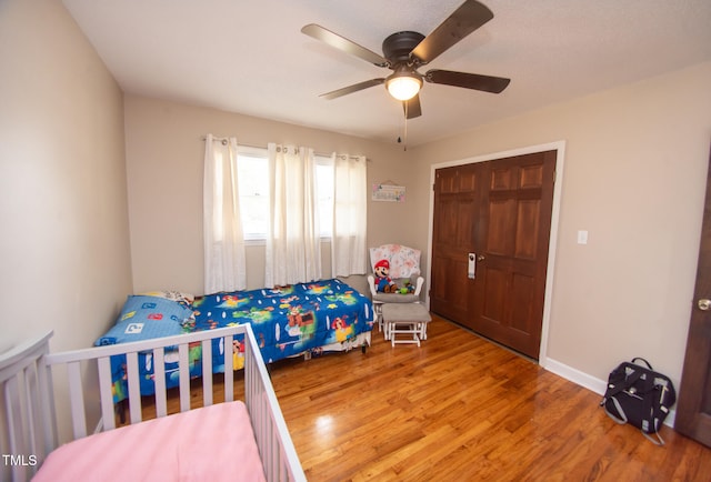 bedroom with ceiling fan, a closet, and wood-type flooring