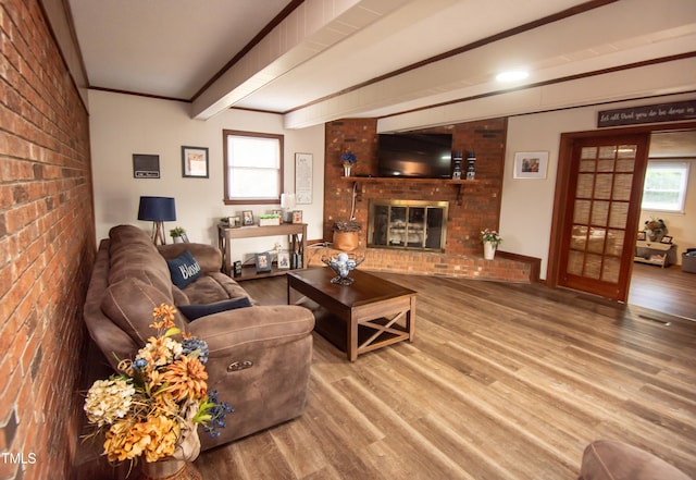 living room featuring hardwood / wood-style flooring, brick wall, a fireplace, and a wealth of natural light