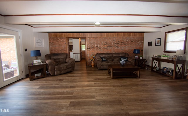 living room featuring beam ceiling, dark hardwood / wood-style flooring, and brick wall