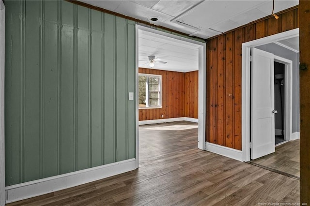 empty room with wood walls, hardwood / wood-style flooring, and ceiling fan