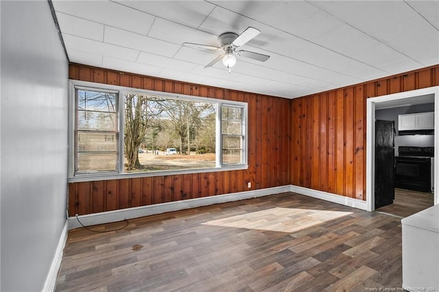 unfurnished room with wood walls, ceiling fan, dark hardwood / wood-style floors, and plenty of natural light