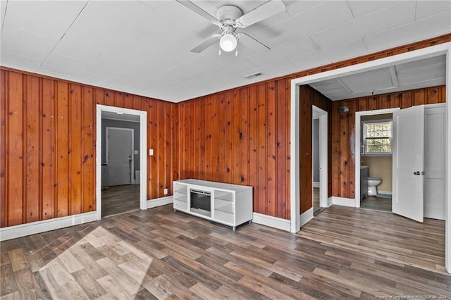 interior space featuring wood walls, ceiling fan, and dark hardwood / wood-style flooring