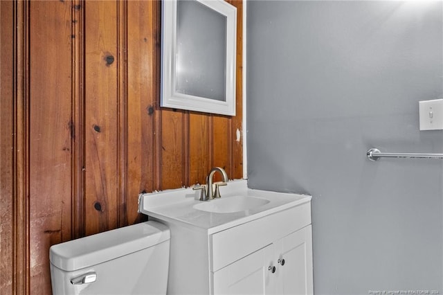 bathroom featuring wood walls, vanity, and toilet