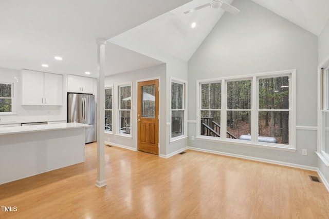 unfurnished living room featuring plenty of natural light, high vaulted ceiling, and light hardwood / wood-style floors