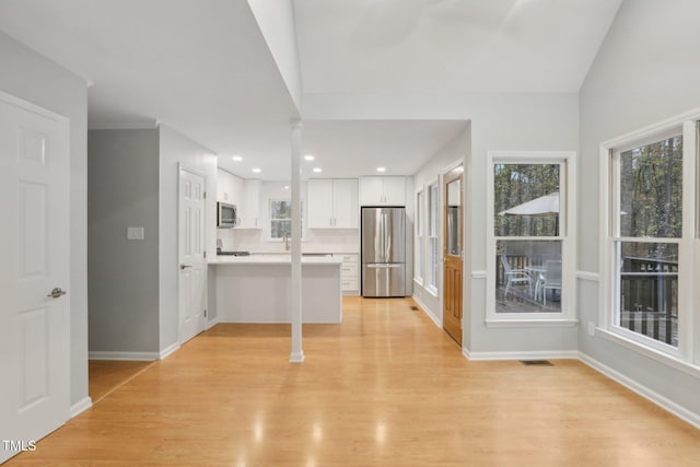 kitchen featuring kitchen peninsula, appliances with stainless steel finishes, white cabinetry, and a wealth of natural light