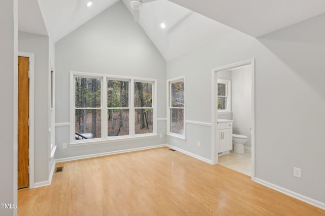 interior space featuring light hardwood / wood-style floors, high vaulted ceiling, and ensuite bath