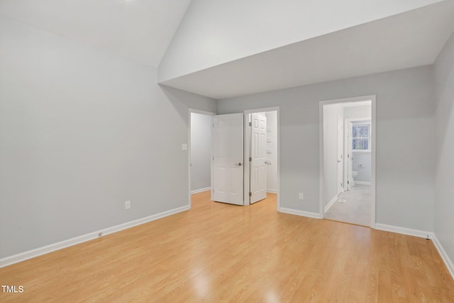 spare room with light wood-type flooring and vaulted ceiling