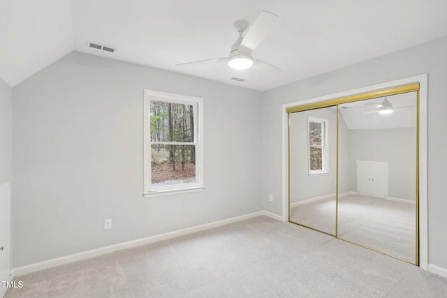 unfurnished bedroom with light carpet, a closet, lofted ceiling, and ceiling fan