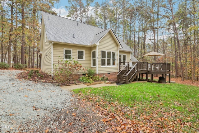 rear view of property featuring a lawn and a deck