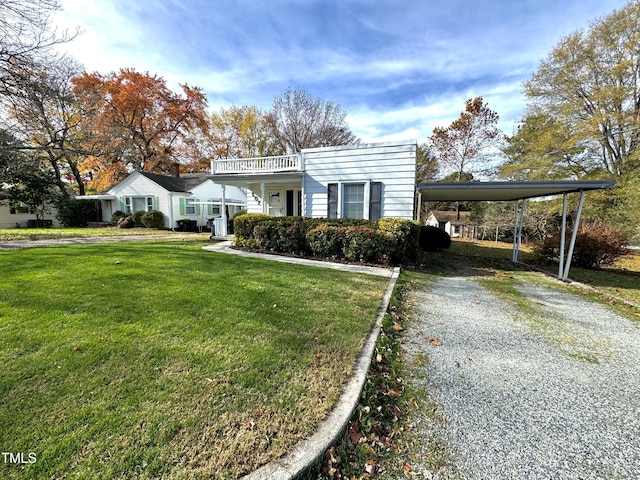 view of front of property featuring a front yard, a balcony, and a carport