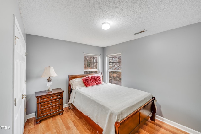 bedroom featuring light hardwood / wood-style floors and a textured ceiling