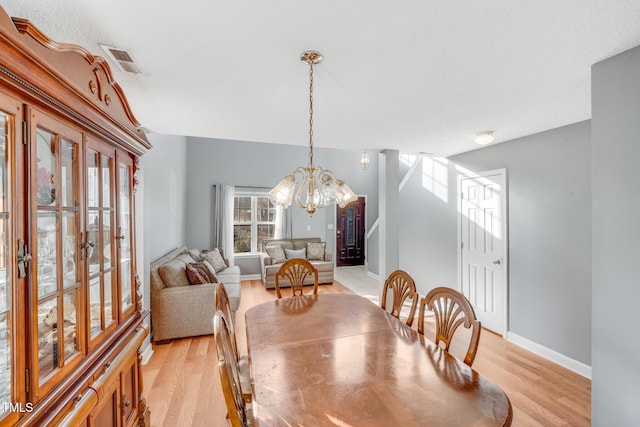 dining area with a chandelier and light hardwood / wood-style flooring