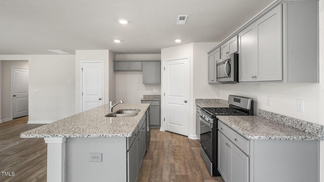 236 Holton St, Smithfield, NC 27577 - kitchen featuring appliances with stainless steel finishes, a sink, gray cabinets, dark wood finished floors, and an island with sink