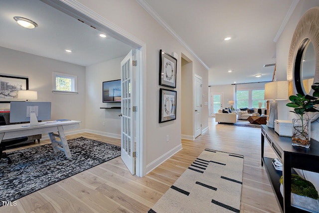 hall with light wood-type flooring, plenty of natural light, and crown molding