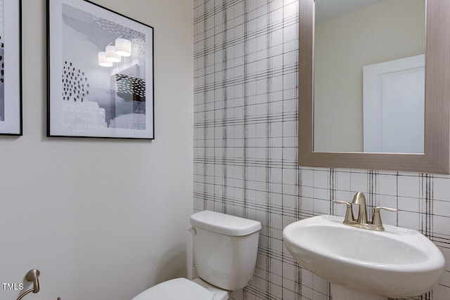 bathroom featuring toilet, sink, and tile walls