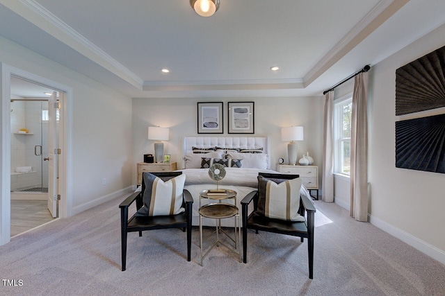 bedroom featuring connected bathroom, light colored carpet, a tray ceiling, and crown molding