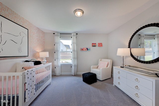 carpeted bedroom featuring a crib and a wall unit AC