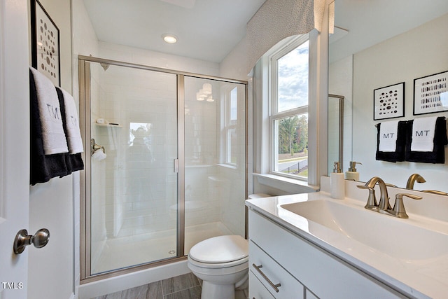 bathroom featuring hardwood / wood-style floors, vanity, a shower with shower door, and toilet