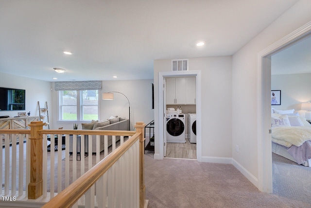 corridor featuring independent washer and dryer and light carpet