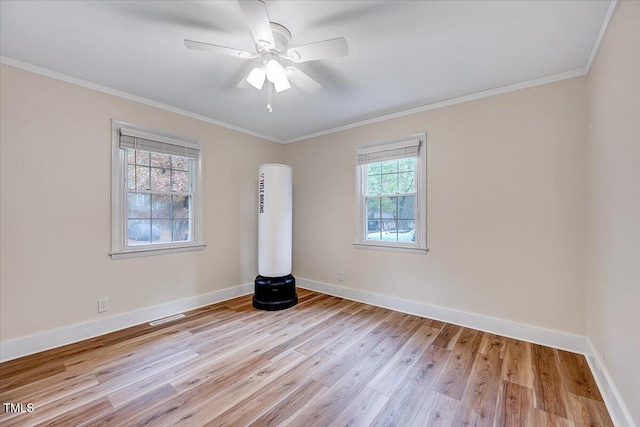 spare room featuring a wealth of natural light, ornamental molding, and light wood-type flooring