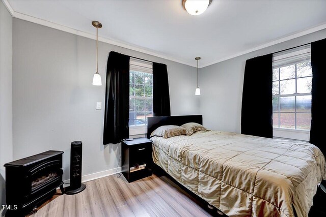 bedroom with hardwood / wood-style floors, multiple windows, and ornamental molding