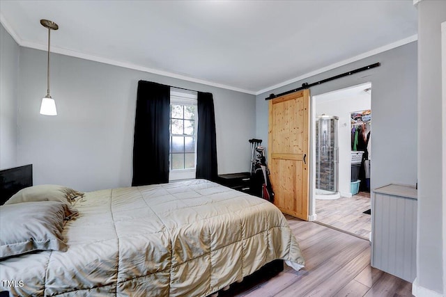 bedroom with ornamental molding, wood-type flooring, a barn door, a spacious closet, and a closet