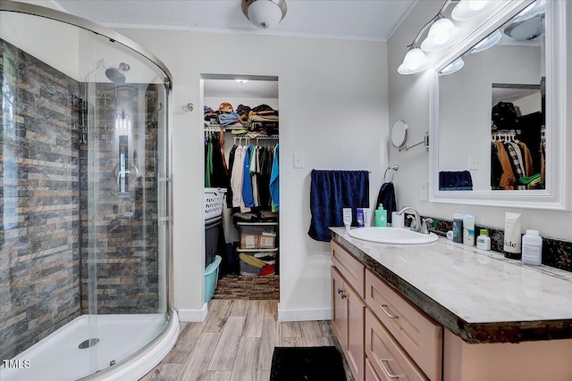 bathroom featuring hardwood / wood-style floors, vanity, ornamental molding, and walk in shower