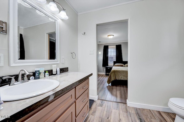 bathroom with vanity, toilet, wood-type flooring, and ornamental molding