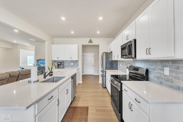 kitchen with light hardwood / wood-style flooring, white cabinets, sink, appliances with stainless steel finishes, and light stone counters