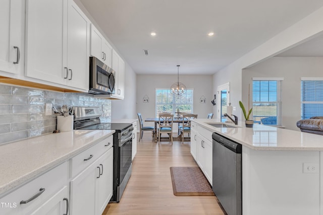 kitchen with white cabinetry, a kitchen island with sink, light hardwood / wood-style flooring, and stainless steel appliances