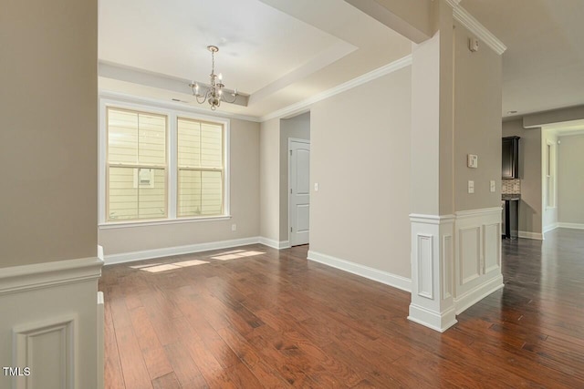 unfurnished room featuring dark hardwood / wood-style flooring, a raised ceiling, crown molding, and an inviting chandelier