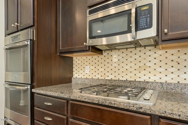 kitchen featuring light stone countertops, appliances with stainless steel finishes, backsplash, and dark brown cabinets