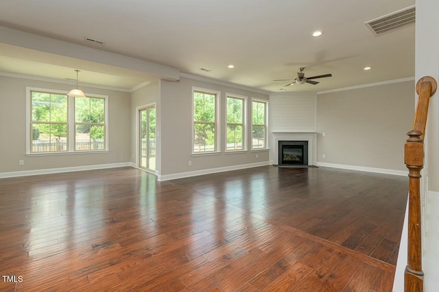 unfurnished living room featuring ceiling fan, a large fireplace, dark wood-type flooring, and ornamental molding